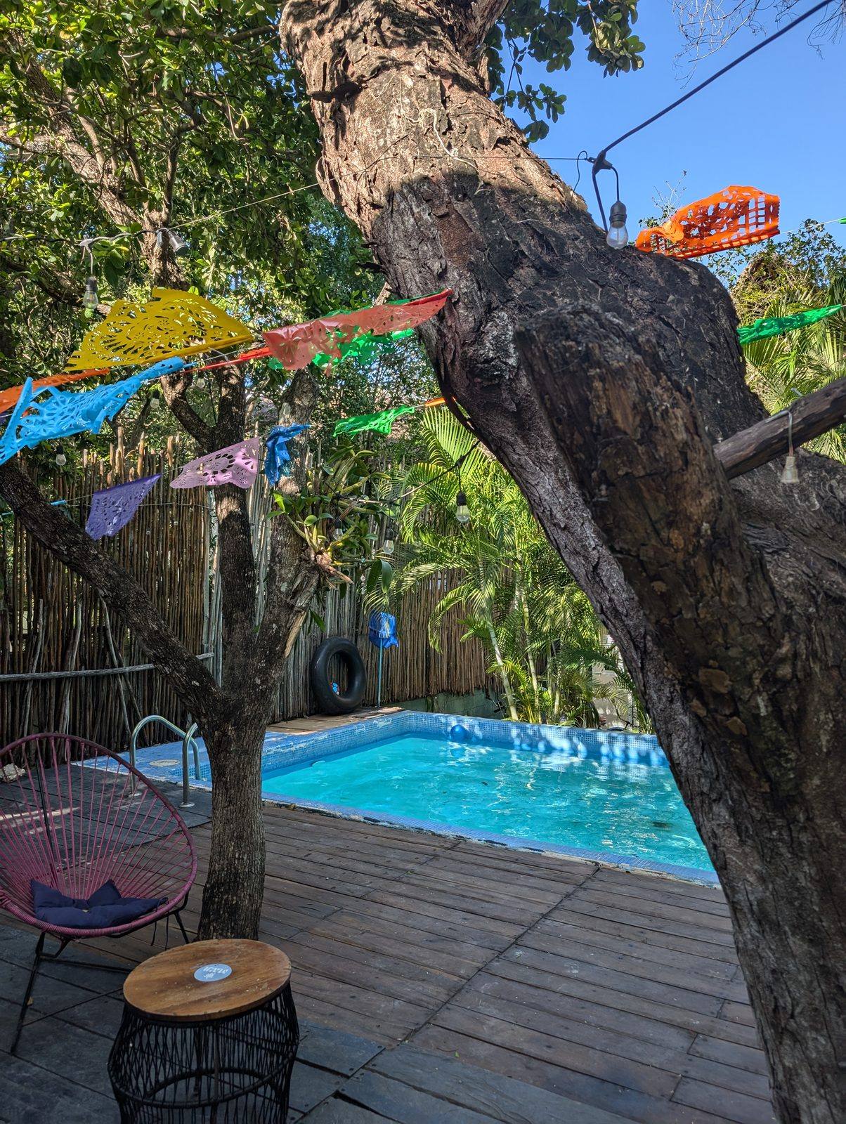 Friends hanging at the jungle pool with papel picado flags — Maui Hostels Tulum